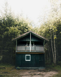 Abandoned house amidst trees in forest against clear sky