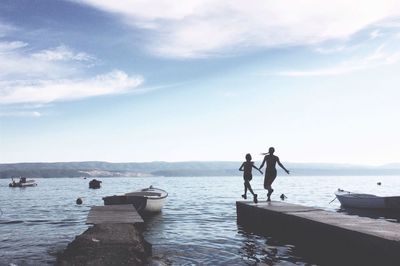 Rear view of siblings on pier against sea