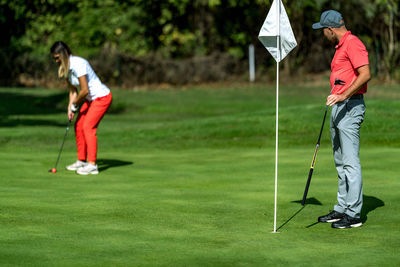 A woman and a man playing golf, woman putting