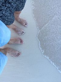 Low section of couple standing at beach