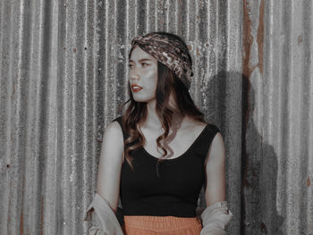 Young woman looking away while sitting on wall