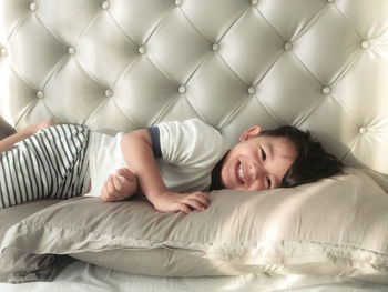 Portrait of a smiling young woman lying on bed at home