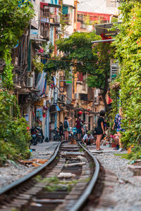 People on railroad tracks amidst buildings in city