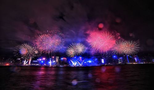 Low angle view of firework display over river at night