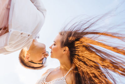 Low angle view of couple kissing against sky
