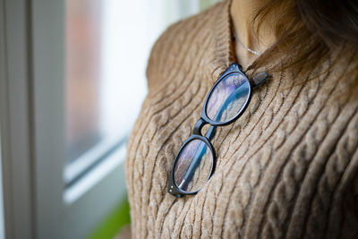 Woman with glasses hanging on her brown sweater.