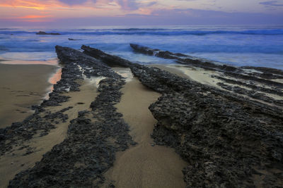 High angle view of rock formations at beach during sunset