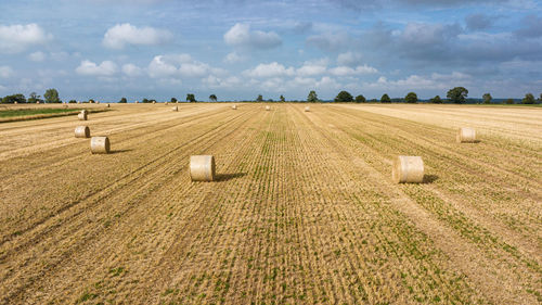 Hay bales on field against sky