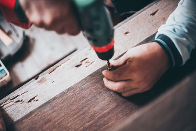 Cropped hands drilling wood