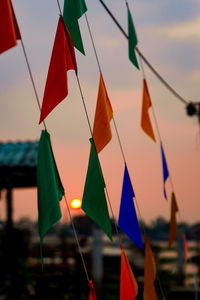 Low angle view of flags hanging against sky during sunset