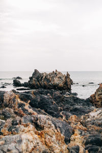 Rock formation on beach against sky