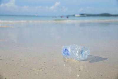 Close-up of water bottle on beach