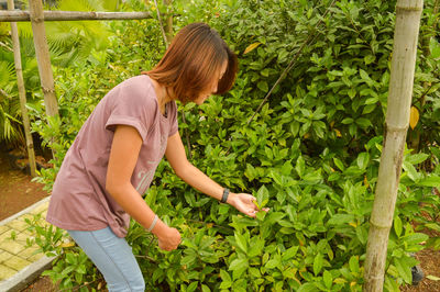 Side view of woman holding plants