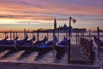 Boats moored in sea at sunset