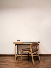 Wooden desk with chair, plants in the room, natural sunlight coming in, pasta tile floor, white pain