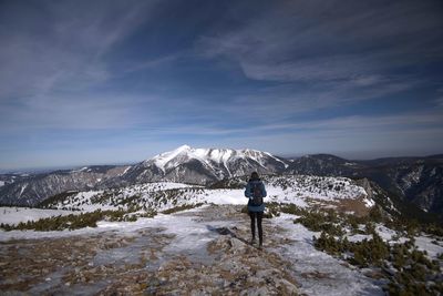 Rear view of person on snowcapped mountain against sky