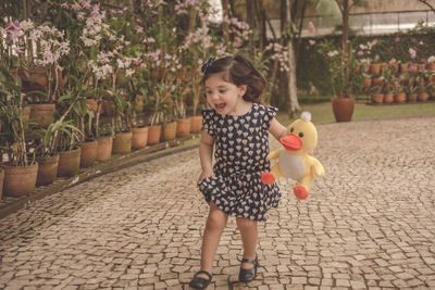 Full length of cute girl with toy standing against plants