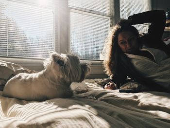 Woman looking at dog relaxing on bed