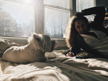 Young woman with dog relaxing on bed at home