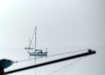 High-key image of yachts in calm sea off eastbourne beach in east sussex as the morning mist lifts.