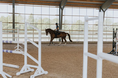 View of female horse rider using indoor riding paddock