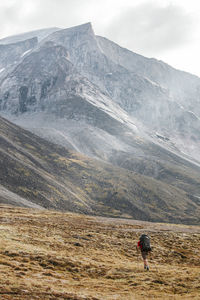 Backpacker hiking below massive granite peak in akshayak pass