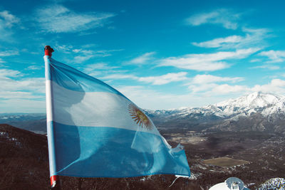 Flag on snowcapped mountain against blue sky