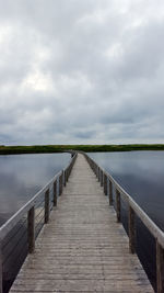 Boardwalk over lake against sky