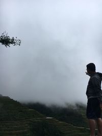 Rear view of man standing on land against sky