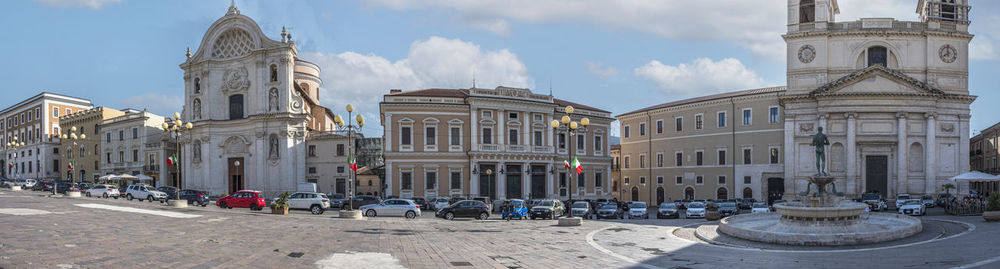 Extra wide angle view of the beautiful piazza duomo in l'aquila with historic buildings and churches