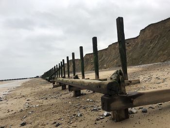 Wooden posts on beach against sky