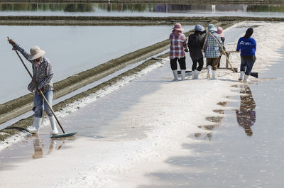 Farmers are using the tools to scoop the salt into a pile in salt garden at phetchaburi, thailand.