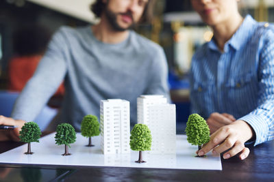 Midsection of business people discussing over architectural model