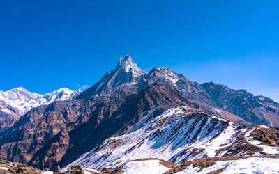 Scenic view of snowcapped mountains against clear blue sky