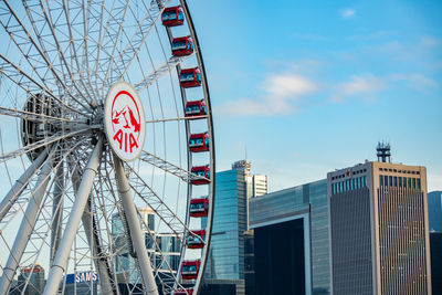 Low angle view of ferris wheel against buildings in city