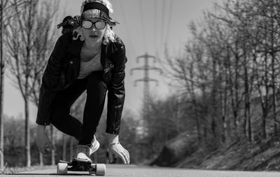 Full length portrait of young woman skateboarding on road