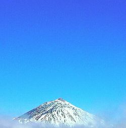 Low angle view of snow covered mountain against blue sky