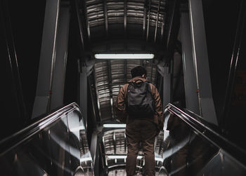 Rear view of man standing on escalator