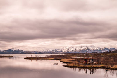 Scenic view of lake against cloudy sky at sunset