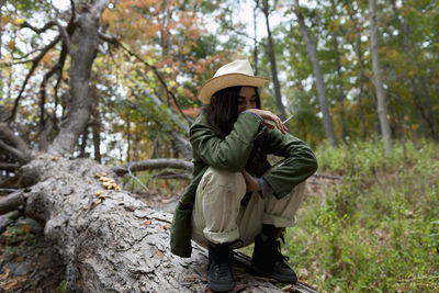 Rear view of woman standing by tree in forest