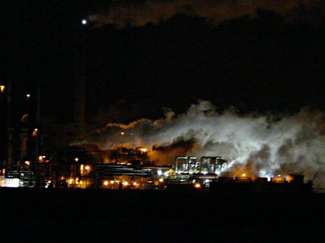 VIEW OF ILLUMINATED FACTORY AGAINST SKY AT NIGHT