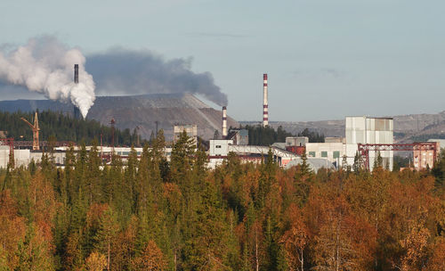 Smoke emitting from factory against sky