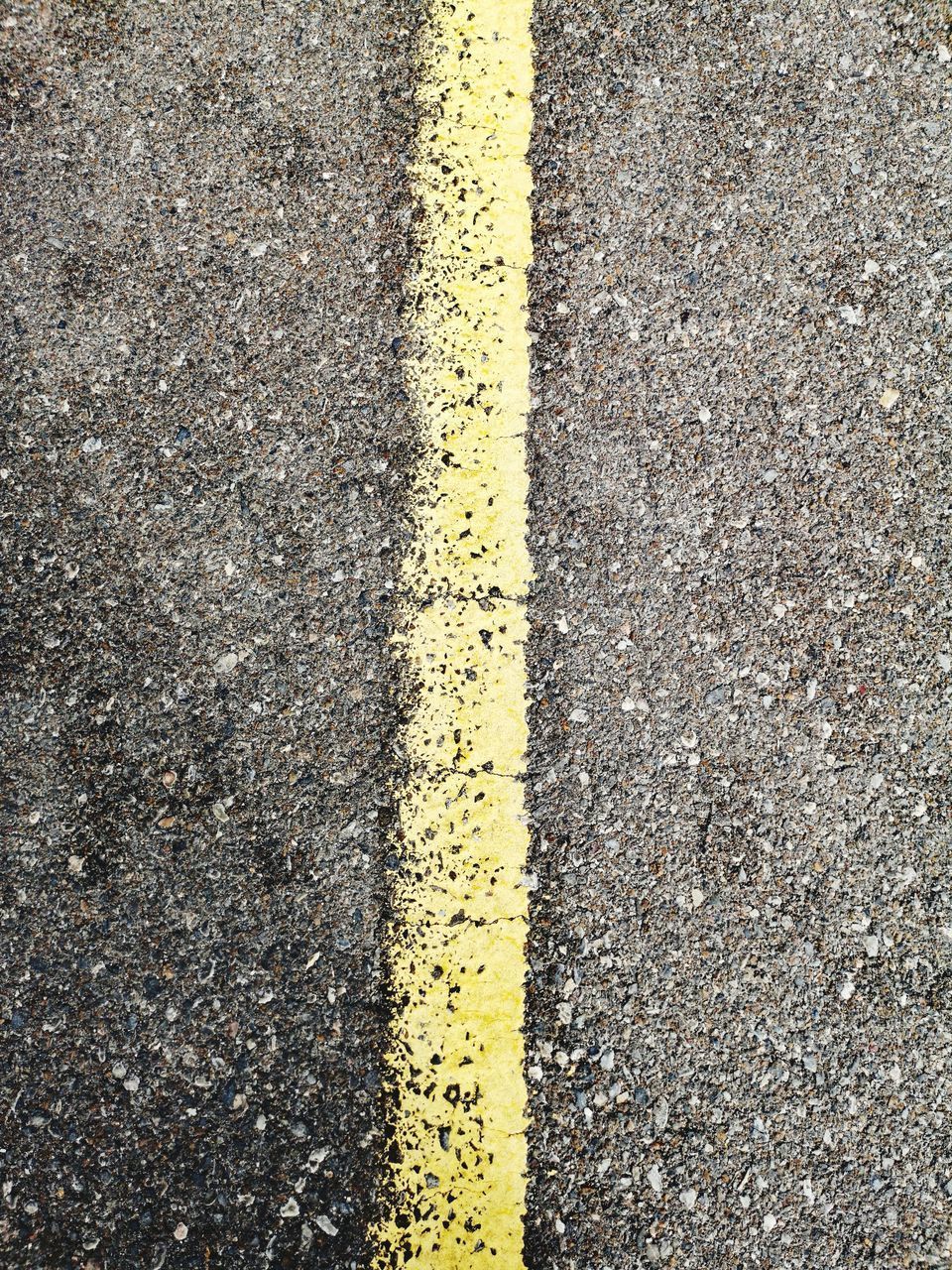 HIGH ANGLE VIEW OF YELLOW ROAD SIGN ON ASPHALT