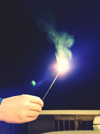 Close-up of hand holding illuminated lights against blue sky