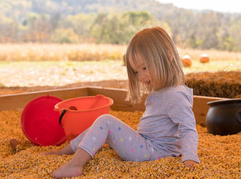 Girl playing with hat sitting outdoors