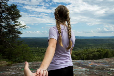 Rear view of woman standing by tree against sky