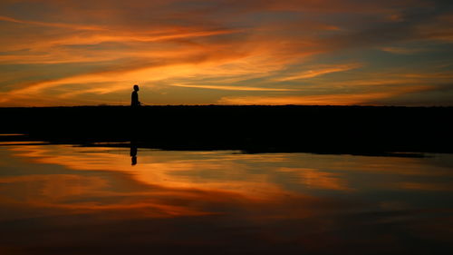 Scenic view of lake against orange sky