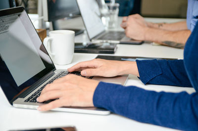 Midsection of man using laptop on table