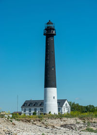 Low angle view of lighthouse by building against clear blue sky