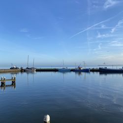 Sailboats in harbor against blue sky